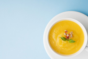 Pumpkin soup mashed with spices in a Cup on a blue background.