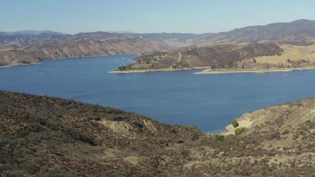 A blue lake in between hills with power boats and kayaks