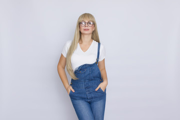 Young blond woman in jeans overalls and glasses