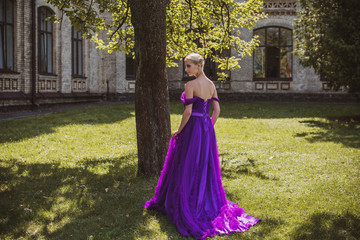 Obraz na płótnie Canvas Vintage clothes concept, girl in evening purple dress in garden