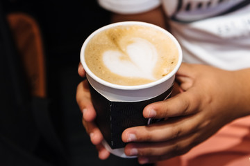 Young male hands holding a cup of coffee drink