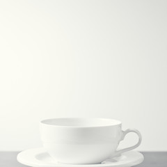 White porcelain tea cup shot against a creamy white background. With copy space.