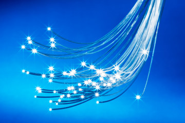 Bundle of optical fibers with lights in the ends. Blue background.