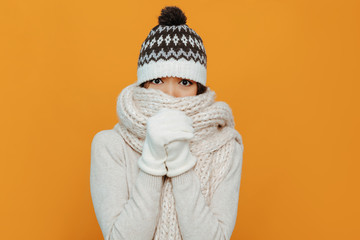 Woman portrait. Accessories. Warmness. Asian girl in a white scarf, cap and gloves is showing she...