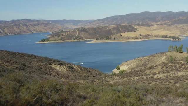A blue lake in between hills with power boats and kayaks