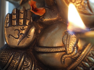 Close up flame in front of a ganesha deity