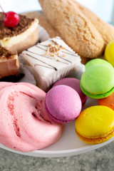 Macaroons, meringues and other sweets on a plate closeup