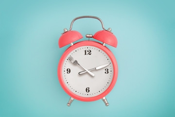 Alarm clock. Fork and knife instead of clock hands. Concept of intermittent fasting, lunchtime,...