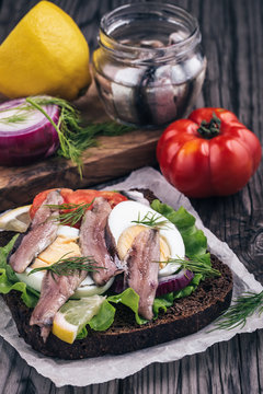 Sandwich with anchovy,egg and tomatoes on table