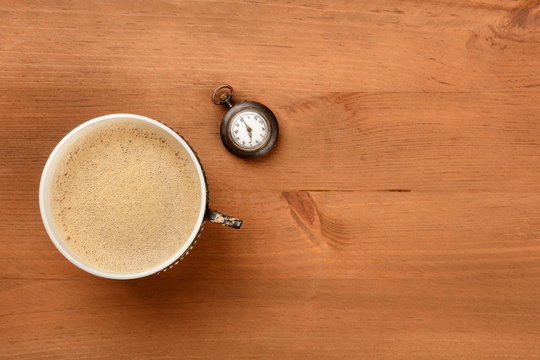 Coffee Time, vintage style. A photo of coffee in a retro cup, shot from above on a rustic wooden background with an old watch and copy space