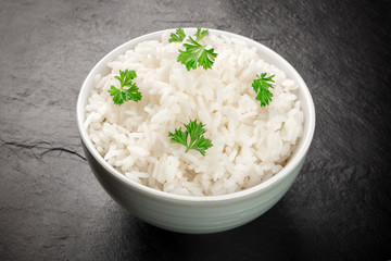 A photo of a bowl of cooked white long rice on a black background with copy space