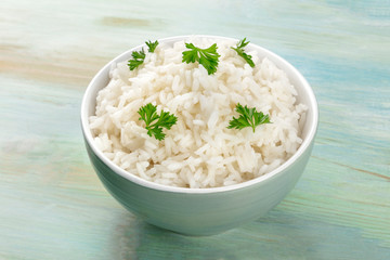 A photo of a bowl of cooked white long rice on a teal blue background with a place for text