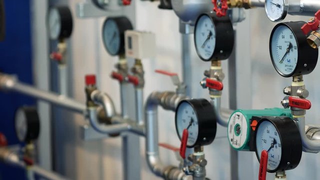 Pipes and valves with gauge pressure controllers on the wall at the exhibition. Close up