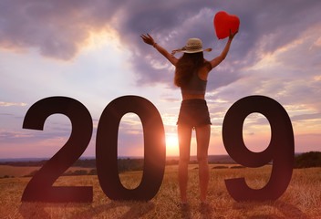 Girl holding balloon in heart shape in hands while celebrating New Year 2019.