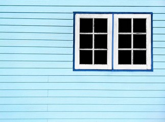 The old white wooden windows on pale blue artificial wood wall background in home decorations concept, vintage style with copy space