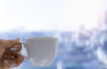 Hand holding a cup of coffee on city background.