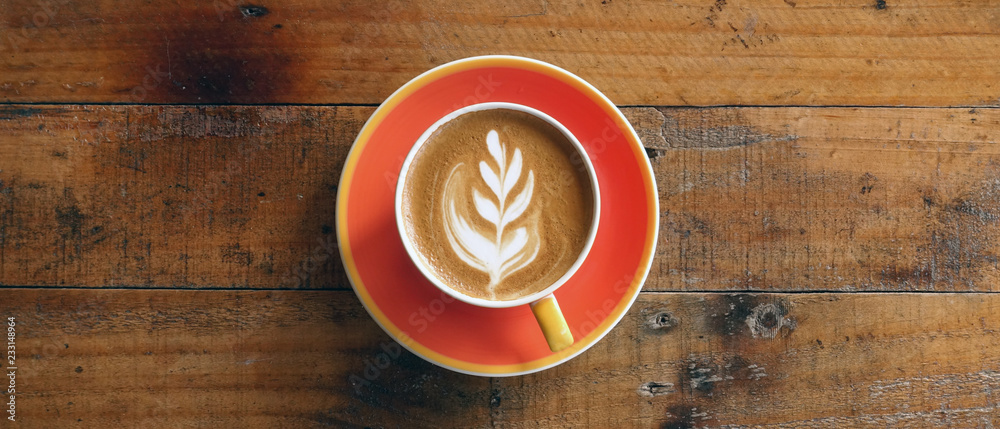 Wall mural a cup of latte art coffee on wooden background