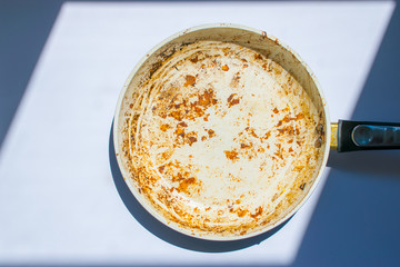 Dirty white ceramic frying pan on the background in window light