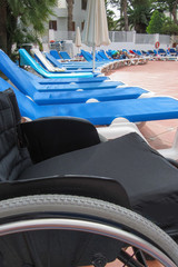 handicapped summer vacation and travel in a wheelchair, wheelchair and blue deck chairs near the pool summer daylight