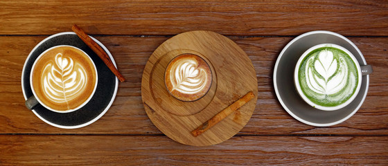 A cup of green tea matcha latte and cup of latte art coffee on wooden background