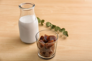 Glass with coffee ice cubes and bottle of milk on wooden table