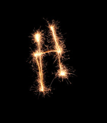 Sparklers forming letter H on dark background