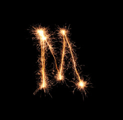 Sparklers forming letter M on dark background