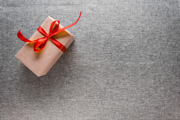 The gift box is wrapped in a red ribbon, on a gray background