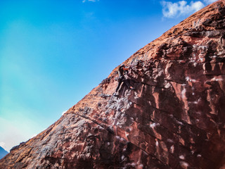 man climbs rock formation in desert