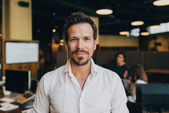 Portrait of confident businessman with earphones in office