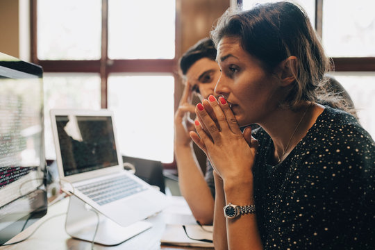 Tensed mid adult businesswoman with hands clasped looking at computer monitor in office