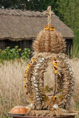 Tradycyjny wieniec dożynkowy upleciony ze suchych zbóż i kwiatów drewniana stodoła i słoneczniki - obrazy, fototapety, plakaty