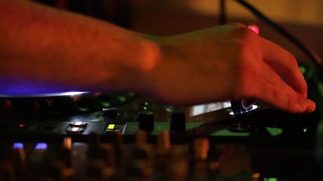Deejay sta lavorando alla sua consolle mettendo musica per la folla che balla in un locale notturno