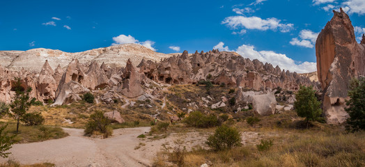 Fototapeta premium Panoramic view from the structure of Cappadocia. Impressive fairy chimneys of sandstone in the canyon near Cavusin village, Cappadocia, Nevsehir Province in the Central Anatolia Region of Turkey.