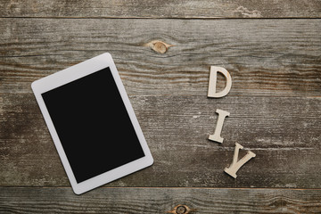 Top view of digital tablet and diy sign on wooden background