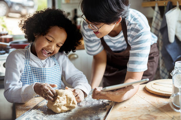 Young boy leaning to bake with his mother - obrazy, fototapety, plakaty