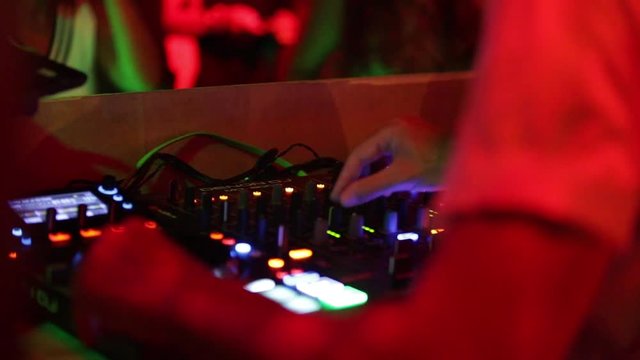 Deejay sta lavorando alla sua consolle mettendo musica per la folla che balla in un locale notturno