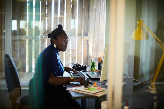 Side view of businesswoman working at computer desk in creative office