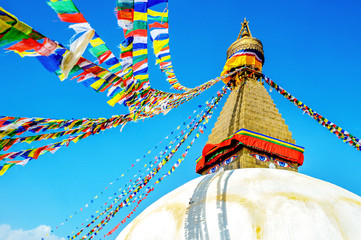 Bodhnath stupa in kathmandu with buddha eyes and prayer flags on clear Blue sky background.