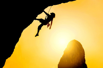 Silhouette of man climbing at sunset. The rock climber during rock conquest. Climbing sport concept.