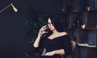 Beautiful brunette woman drinking red wine sitting in room