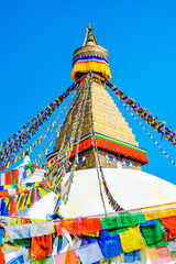 Bodhnath stupa in kathmandu with buddha eyes and prayer flags on clear Blue sky background.
