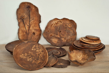 Clay pottery and ceramic products on a wooden table. Home workshop. Handmade with drawings and patterns.