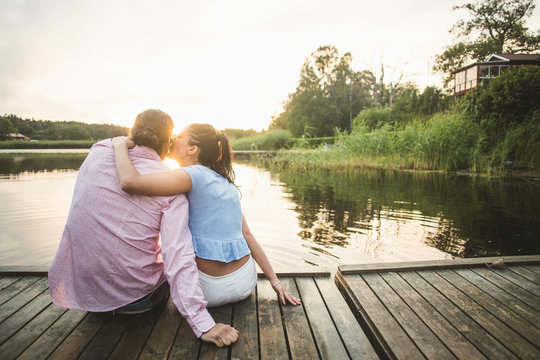 Woman kissing boyfriend on dock during sunset
