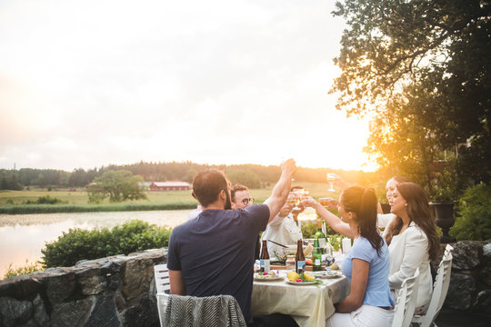 Friends toasting drinks at dining table during sunset