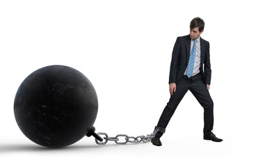 Young businessman has chained big metal ball to his leg. Isolate