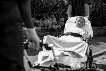 Paramedics moving a young patient on a stretcher to an ambulance