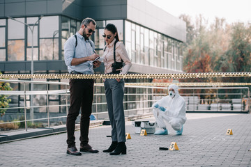 female and male detectives review their records at crime scene
