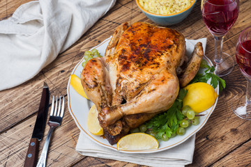 Baked chicken, wine glasses and fruit for dinner on the festive table.