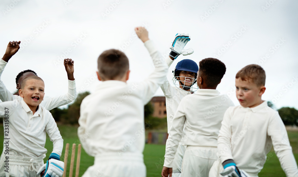 Wall mural young happy cricketers cheering on the field